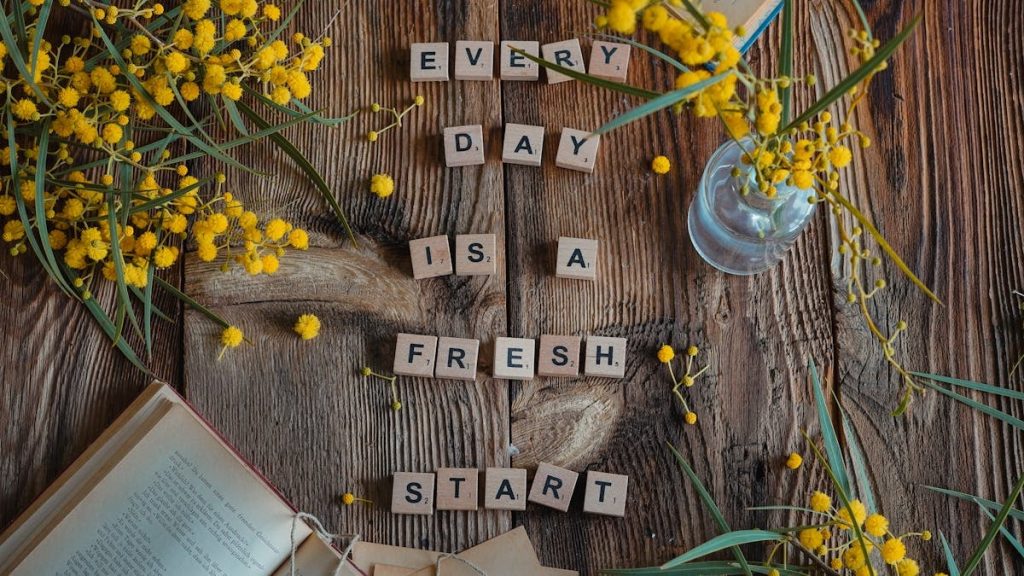 Flat lay of rustic wood, yellow flowers, and motivational quote.